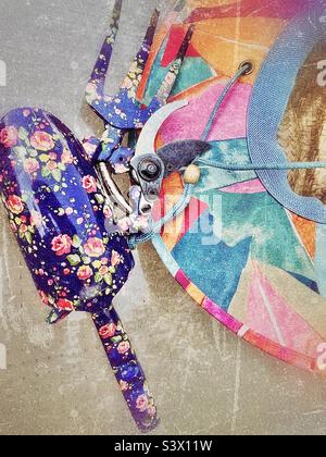 Attrezzi di una donna giardiniera per lavorare nel suo cortile/giardino - un cappello di paglia colorato, e cesoie per potare fiori, vanga e artiglio. Effetto grunge aggiunto digitalmente a questa vita morta all'aperto. Foto Stock