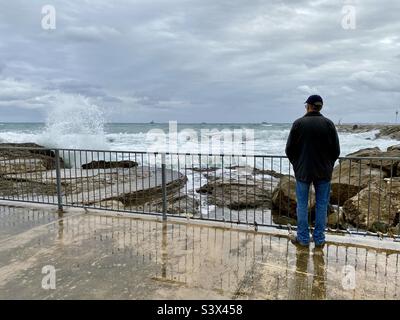 Uomo in piedi da ringhiere su una costa rocciosa in inverno Foto Stock
