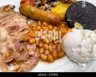 Bacon, uova in camicia, fagioli al forno, salsicce, crocchette di patate e budino nero prima colazione Foto Stock