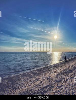 Camminando come il tramonto sulla spiaggia vicino Leigh-on-Sea, Essex. L'estuario del fiume Tamigi è tranquillo in una serata di settembre Foto Stock