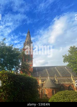 Vista di St John the Divine, Kennington, South East London, edificio classificato di primo livello, visto dai Giardini Dan Leno - Dan Leno vissuto nelle vicinanze - la guglia della chiesa è imponente e ha un orologio. Foto Stock