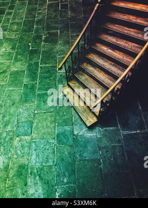 Vista ad alto angolo di una vecchia scala in legno che si avvolge verso il basso in una malvagia stalla o scantinato scuro con luce verde e spazio copia Foto Stock