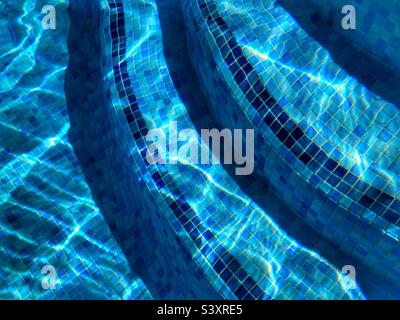 Dettaglio piscina, gradini piastrellati blu con rifrazione e increspature chiare. Sfondo astratto Foto Stock