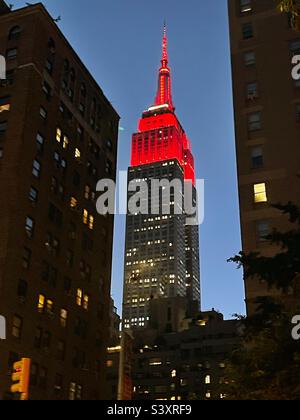 La Red Tower si illumina in cima all'Empire state Building in prima serata, visto da 35th St. E Park Avenue a New York City, USA, 24 settembre 2022 Foto Stock