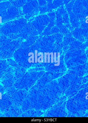 Acqua in piscina nelle calde giornate estive. Piastrelle blu e ripple scintillanti. Un'immagine delle vacanze estive. Foto ©️ COLIN HOSKINS. Foto Stock