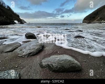 Le onde si sovrapponono alle rocce a Lee Bay in Somerset inglese sulla spiaggia in inverno Foto Stock