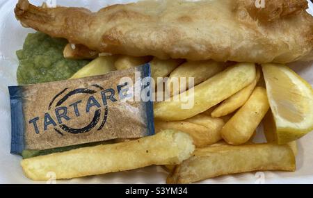 Patatine di pesce e piselli con salsa tartare e un spicchio di limone Foto Stock