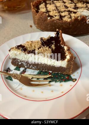 Deliziosa cheesecake al cioccolato su un piatto di Natale con una forchetta per torte dorate Foto Stock