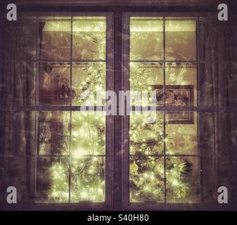 Un bellissimo albero artificiale di Natale di abete, illuminato da luci bianche, visto dall'esterno di questa casa dello Utah. L'app IOS Snapseed è stata utilizzata per dare all'immagine una texture e un look vintage e grunge. Foto Stock