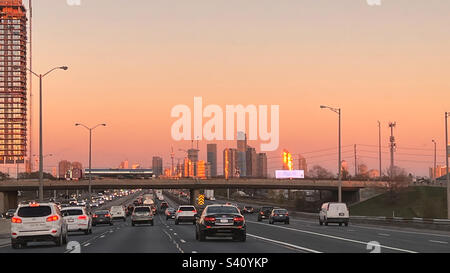 Dirigiti a Toronto sulla Queen Elizabeth Highway al tramonto nel traffico Foto Stock