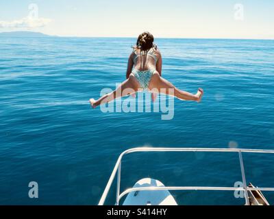 Una donna fa le divisioni mentre salta da una barca in Costa Rica Foto Stock