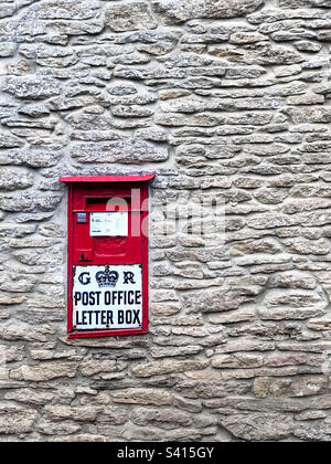 Una scatola da cartolina inglese rossa su un muro di pietra di Cotswolds Foto Stock