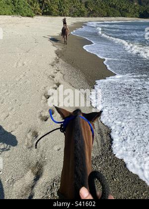 Due persone a cavallo godono di un giro lungo la spiaggia di Santa Teressa Costa Rica Foto Stock