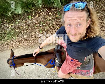 Un uomo prende un selfie mentre si cavalca nella foresta in Costa Rica Foto Stock