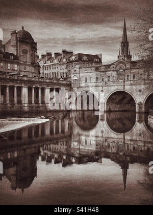 Un'immagine retrò del famoso Pultney Bridge e Weir a Bath, Inghilterra. Interessanti riflessioni sono state create nel fiume Avon. Bath è una delle principali destinazioni turistiche del Regno Unito. Foto ©️ COLIN HOSKINS. Foto Stock