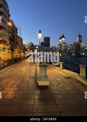 Promenade di notte, pedoni che camminano lungo il marciapiede e un sentiero scivoloso giù per le barche da pesca di notte. Foto Stock