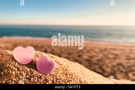 Vista a basso angolo di due cuori di caramelle rosa sulla spiaggia. Concetto spiaggia matrimonio, amore, luna di miele Foto Stock
