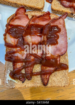 Sandwich con pancetta su pane integrale con salsa di colore marrone Foto Stock