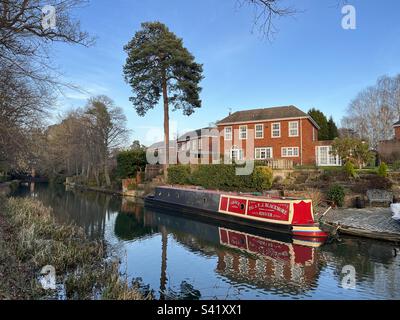 Accanto a una proprietà sul canale di Basingstoke a Fleet, Hampshire, è ormeggiata una barca per i canali. Completato nel 1794, costruito per collegare Basingstoke con il Tamigi a Weybridge tramite la Wey Navigation. Foto Stock