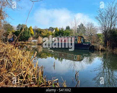 Accanto a una proprietà sul canale di Basingstoke a Fleet, Hampshire, è ormeggiata una barca per i canali. Completato nel 1794, costruito per collegare Basingstoke con il Tamigi a Weybridge tramite la Wey Navigation. Foto Stock