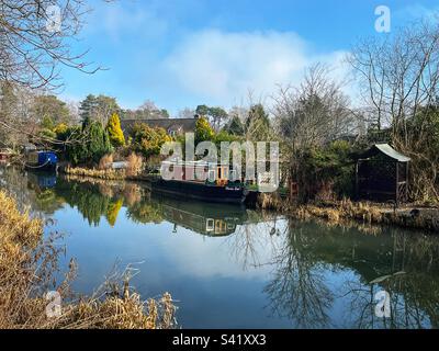 Accanto a una proprietà sul canale di Basingstoke a Fleet, Hampshire, è ormeggiata una barca per i canali. Completato nel 1794, costruito per collegare Basingstoke con il Tamigi a Weybridge tramite la Wey Navigation. Foto Stock