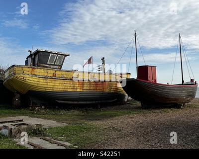 Due vecchie barche da pesca in legno in decadenza sulla spiaggia di Hastings, East Sussex, Inghilterra Foto Stock