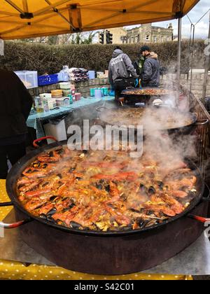 Primo piano vapore che sale da Paella Pan Cooking Seafood Paella Street food spagnolo al mercato agricolo locale nel Regno Unito Foto Stock