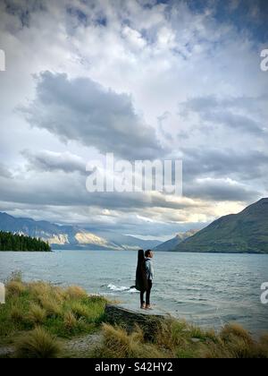 Un musicista con una chitarra sul retro che guarda fuori sul Lago Wakatipu vicino Queenstown, nell'Isola del Sud della Nuova Zelanda Foto Stock