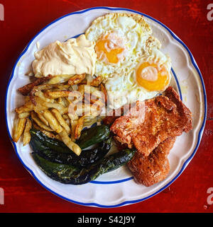 Due uova fritte, patate fritte, peperoni verdi fritti e carne con peperoncino a Queretaro, Messico Foto Stock