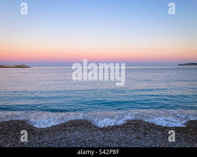 Tramonto sul mare visto dalla spiaggia di ciottoli nella zona del porto di Javea sulla Costa Blanca, Provincia di Alicante, Comunidad Valencia, Spagna Foto Stock