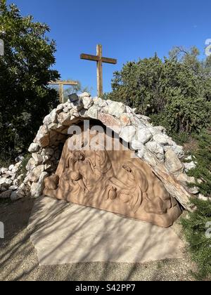 Gesù posò nella Tomba, 14th Stazione, Vergine Maria, Canaan nel deserto, Phoenix, Arizona, la Sisterhood evangelica di Maria, la grotta, il cielo blu luminoso, la croce vuota sullo sfondo, raggiungendo le ombre Foto Stock