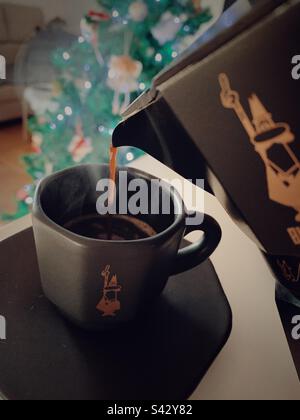 Versare il caffè dalla moka bialetti alla tazza espresso Foto Stock