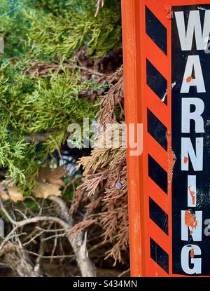 Il simbolo arancione di metallo sulla destra indica UN AVVERTIMENTO. Alberi sullo sfondo. Include lo spazio di stampa. Foto Stock