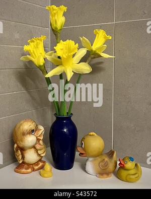Bathroom still life. Daffodils in blue vase and yellow rubber ducks Foto Stock