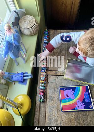 Ragazzo che gioca con i suoi treni giocattolo Foto Stock