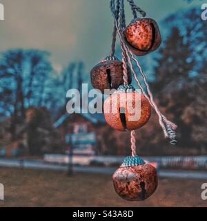 Piccole campane ornamentali appese ad un albero nel parco Singleton Swansea, Galles del Sud. Con un cottage di tipo svizzero sullo sfondo. Foto Stock