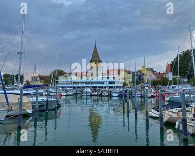 Vista del tramonto al porto di Lindau con barche e la torre medievale di Mangturm sul lago Bodensee in Germania. Foto Stock