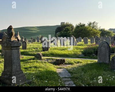 Cimitero della chiesa di San Nicola al tramonto in una calda e soleggiata serata estiva con la cappella di Santa Caterina sulla collina sullo sfondo, Abbotsbury, Dorset, Inghilterra Foto Stock