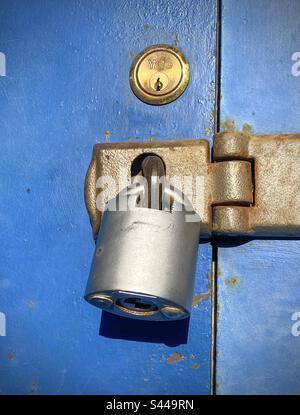 Un grande lucchetto su una porta blu al sole del mattino Foto Stock