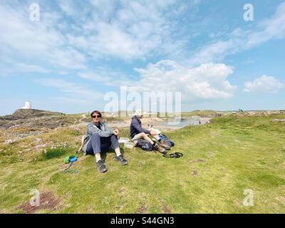 Gli escursionisti che si godono la vista sull'isola di Llandwyn da Pilot's Cove, Newborough, Anglesey, Galles del Nord Foto Stock