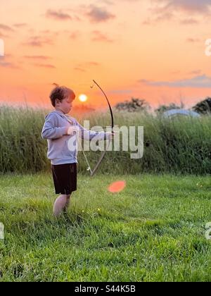 Boy prova un arco giocattolo e una freccia nei prati e nel campeggio inglesi Foto Stock