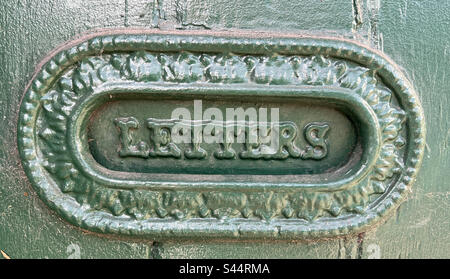 Slot per lettere vecchio stile su una porta verde Foto Stock