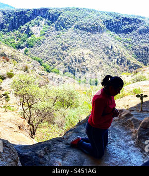 Una donna che si inginocchiava e pregava durante una messa in memoria dei cristeri cattolici uccisi nella guerra di Cristiada sulle montagne di El Zamorano a Colon, Queretaro, Messico Foto Stock