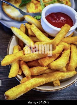 Primo piano di patatine fritte con ketchup in una piccola ciotola sul tavolo. Cibo di conforto. Mangiare malsano. Contorno. Foto Stock
