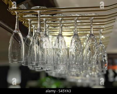 Flauti di champagne appesi a un portabagagli sopra un bar di un ristorante Foto Stock