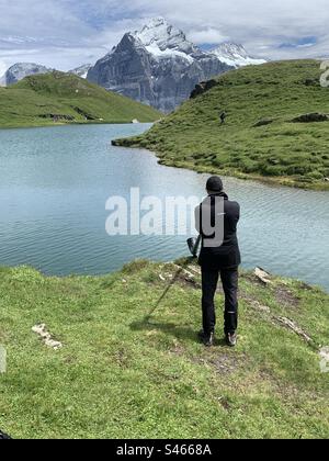 Uomo che suona corno lungo al lago Bachsee Swiss alps Foto Stock