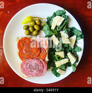 Un sandwich di salame e chorizo spagnolo con insalata di rucola con formaggio e olive e peperoncino piccante giallo cascabella a Queretaro, Messico Foto Stock