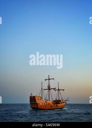 Vecchia nave in stile Game of Thrones che naviga accanto alla città vecchia di Dubrovnik (AKA) l'approdo del re nella serie HBO. Croazia. Foto Stock