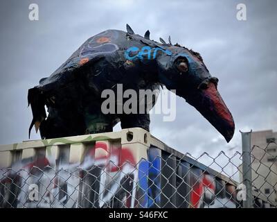 LOS ANGELES, CA, DEC 2022: Grande scultura di cartapesta di corvo nero si trova sulla sommità di un container cargo con graffiti visibili nel centro città. Cieli sovrastati Foto Stock