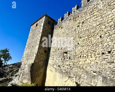 A small tower and walls of the Guaita fortress, first tower, in San Marino against a clear blue sky Foto Stock